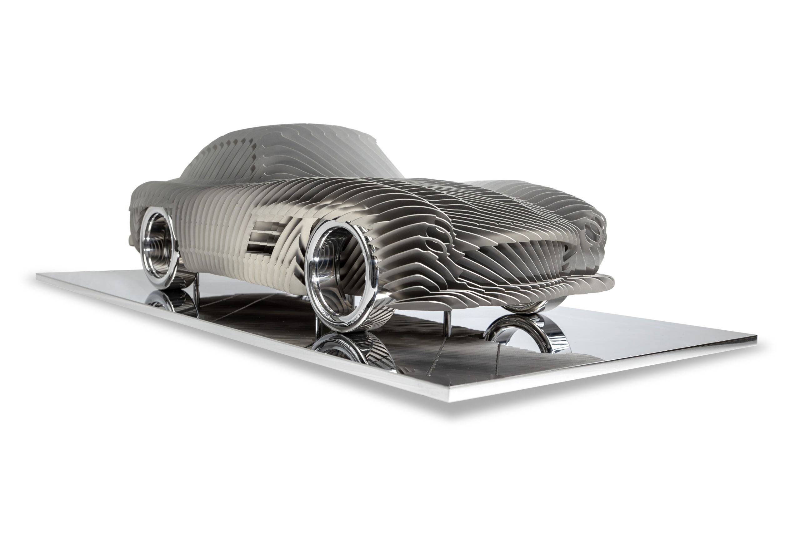 Antoine Dufilho – Mercedes 300 SL Streamline Crème Het kunstwerk Mercedes 300 SL Streamline Crème van Antoine Dufilho is een ode aan snelheid en elegantie. Het werk toont de iconische Mercedes 300 SL in een futuristische interpretatie. De sculptuur bestaat uit gelaagde, gestroomlijnde vormen die ritme en beweging suggereren. Elke lijn benadrukt de vloeiende dynamiek van de auto. Het samenspel van open ruimte en volume geeft het werk een lichtheid, alsof het zweeft. De sculptuur trekt direct de aandacht. Strakke lijnen wisselen af met subtiele rondingen, waardoor een harmonieus beeld ontstaat. Het gebruik van crème- en metaaltinten versterkt het gevoel van luxe en raffinement. Bovendien wordt de auto getoond als meer dan een voertuig: het is een symbool van vooruitgang, design en techniek. Dufilho weet met dit werk een balans te vinden tussen abstractie en herkenning. Van dichtbij zie je de ritmische structuren. Van verder weg herken je duidelijk de iconische Mercedes. Daardoor krijgt het werk meerdere lagen en nodigt het uit tot langer kijken. Het is zowel modern als tijdloos.