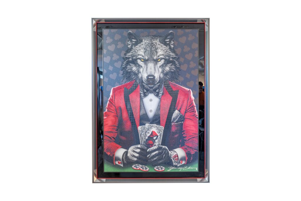 Yaniv Edery - Wolf Poker Red Suit This artwork exudes power and elegance. A wolf in a stylish red suit, sitting at the poker table. The animal holds the cards firmly and looks confidently ahead. The red suit symbolizes boldness and dominance. At the same time, the black shirt with bow tie adds a touch of sophistication and class. The background shows subtle heart patterns, emphasizing the tension of the game. The contrast between the dark wolf head and the bright red makes the work intense and compelling. Every detail - from the fine lines in the fur to the perfectly depicted chips - contributes to an image that makes an immediate impression. This work of art shows how instinct, style and power come together. It is more than a decorative piece: it tells a story. About strategy, risk and the power to win. That makes Wolf Poker Red Suit ideal for those looking for a strong and expressive piece of art that combines class and character.