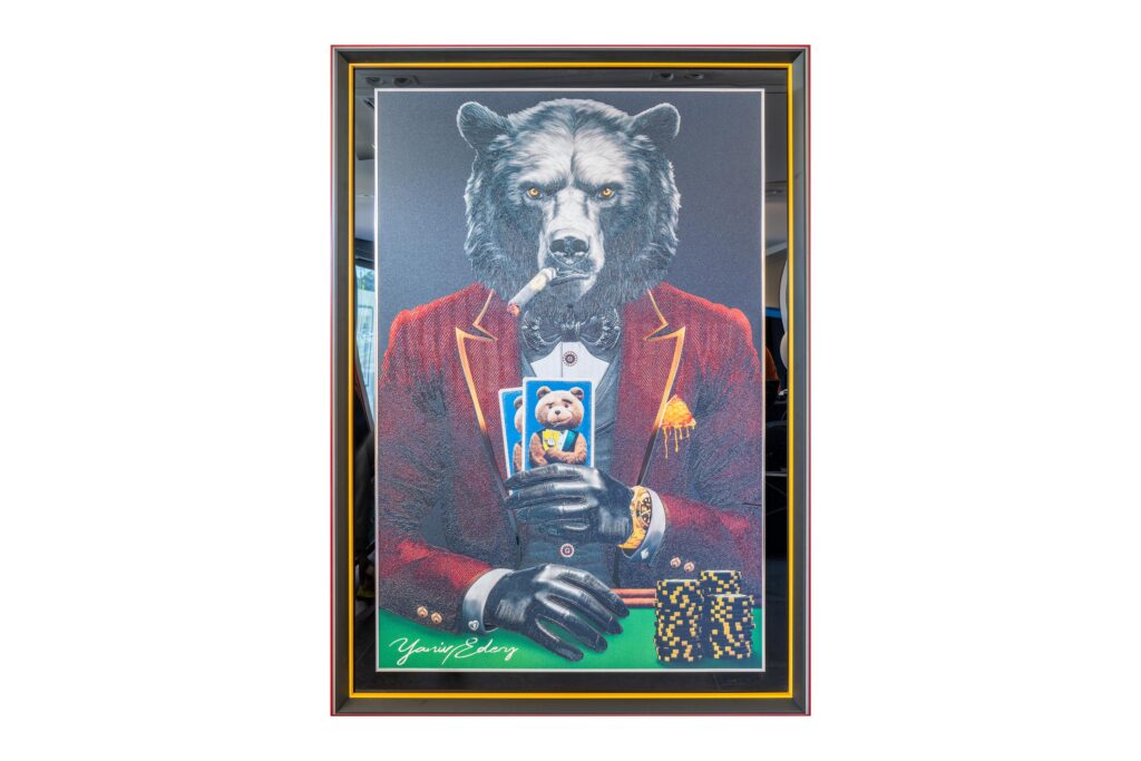 Yaniv Edery - Bear Pok'Art Red Suit is a work of art that exudes instant power and elegance. The imposing bear sits stylishly at the poker table, dressed in a deep red suit with black accents. He holds his cards firmly, ready to outwit his opponents. The gold details, watch and chips enhance the aura of luxury and power. This piece tells a story of strategy, excitement and dominance. The bear symbolizes strength, determination and natural authority. His gaze is intense and unrelenting, as if he is in complete control. The combination of poker and animal power makes this artwork both playful and impressive. The red suit is more than fashion. It represents guts, passion and energy. Combined with the dark background and light contrasts, it creates a composition that continues to fascinate. Every detail, from the smoke of the cigar to the sharp lines of the suit, is carefully crafted and exudes Yaniv Edery's signature style. In this work, the symbolism of poker - risk, patience and strategy - comes together perfectly with the natural force of the bear. This creates a work of art that invites reflection, but at the same time is a powerful eye-catcher in any space.