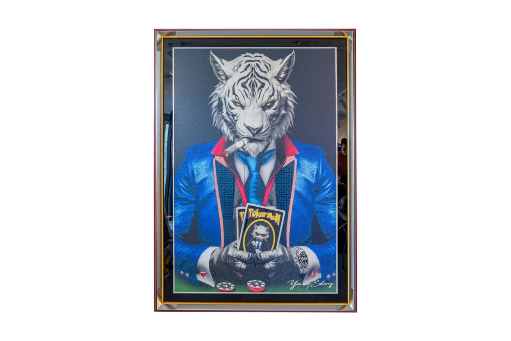 Yaniv Edery - Tiger Pok'Art Blue Suit Medium is a powerful and intriguing work of art. It depicts a tiger figure, stylishly dressed in a blue suit, sitting at the poker table with a confident look. The cigar between his teeth and the cards in his hand reinforce his dominant appearance. This work exudes power, excitement and prestige. It combines playful irony with a luxurious look, immediately attracting attention. The clean lines, bright colors and sharp contrasts make this artwork a real eye-catcher. The tiger symbolizes power, courage and strategy, while the poker represents risk, guts and success. Together they create a surprising visual dialogue that continues to intrigue. This work is not just a painting, it is a statement. Ideal for those who want to give their interiors an iconic and contemporary look.